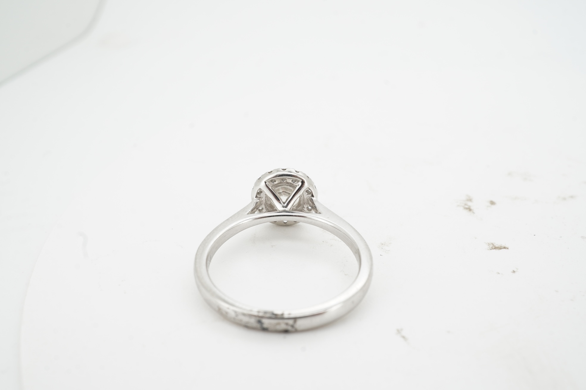 A diamond cluster ring, claw-set with a brilliant-cut diamond weighing approximately 0.70 carats, within a border of smaller brilliant-cut diamonds totalling approximately 0.10 carats, mounted in platinum, size M, Britis